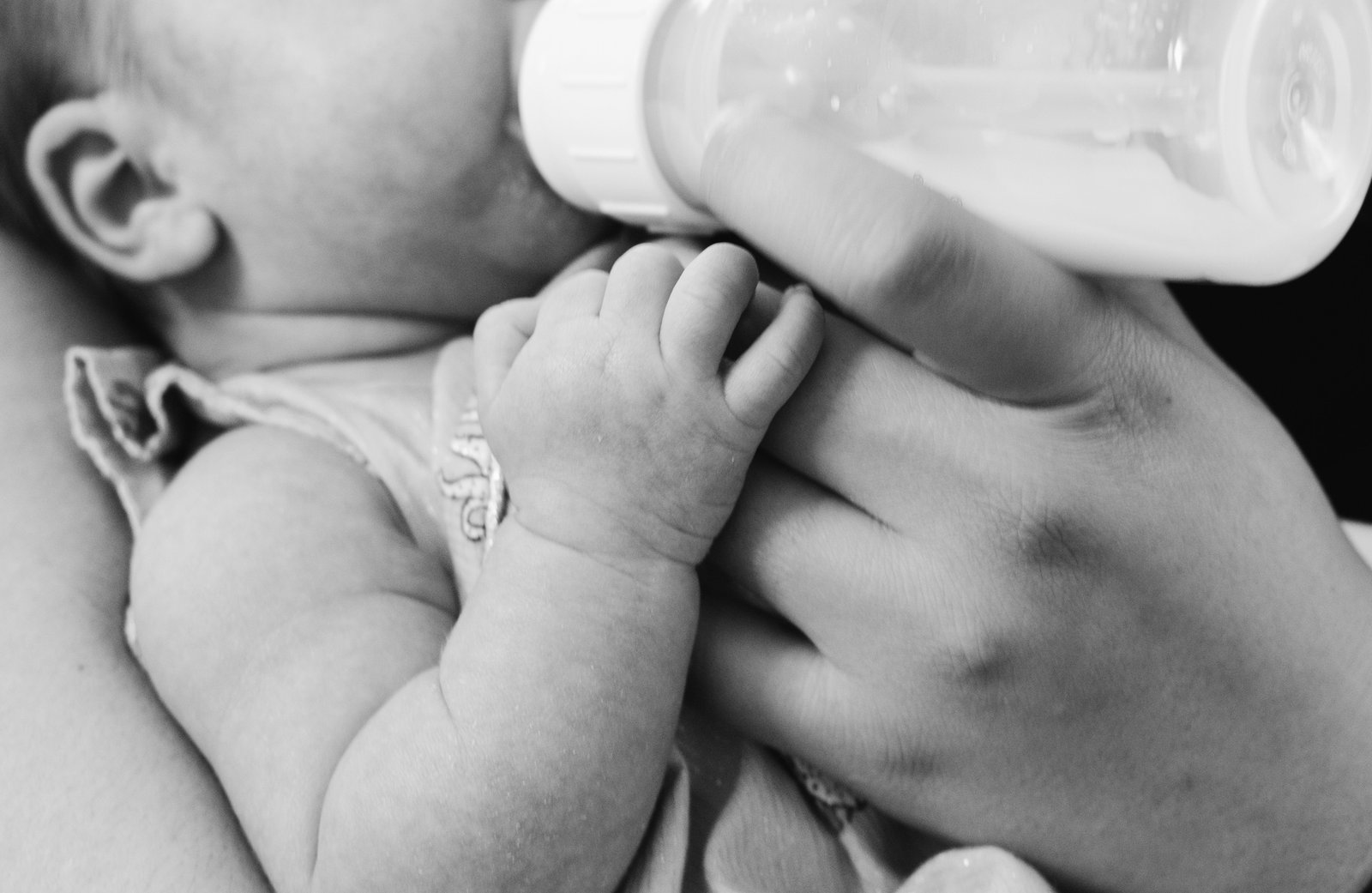 A parent bottle-feeding a baby at home