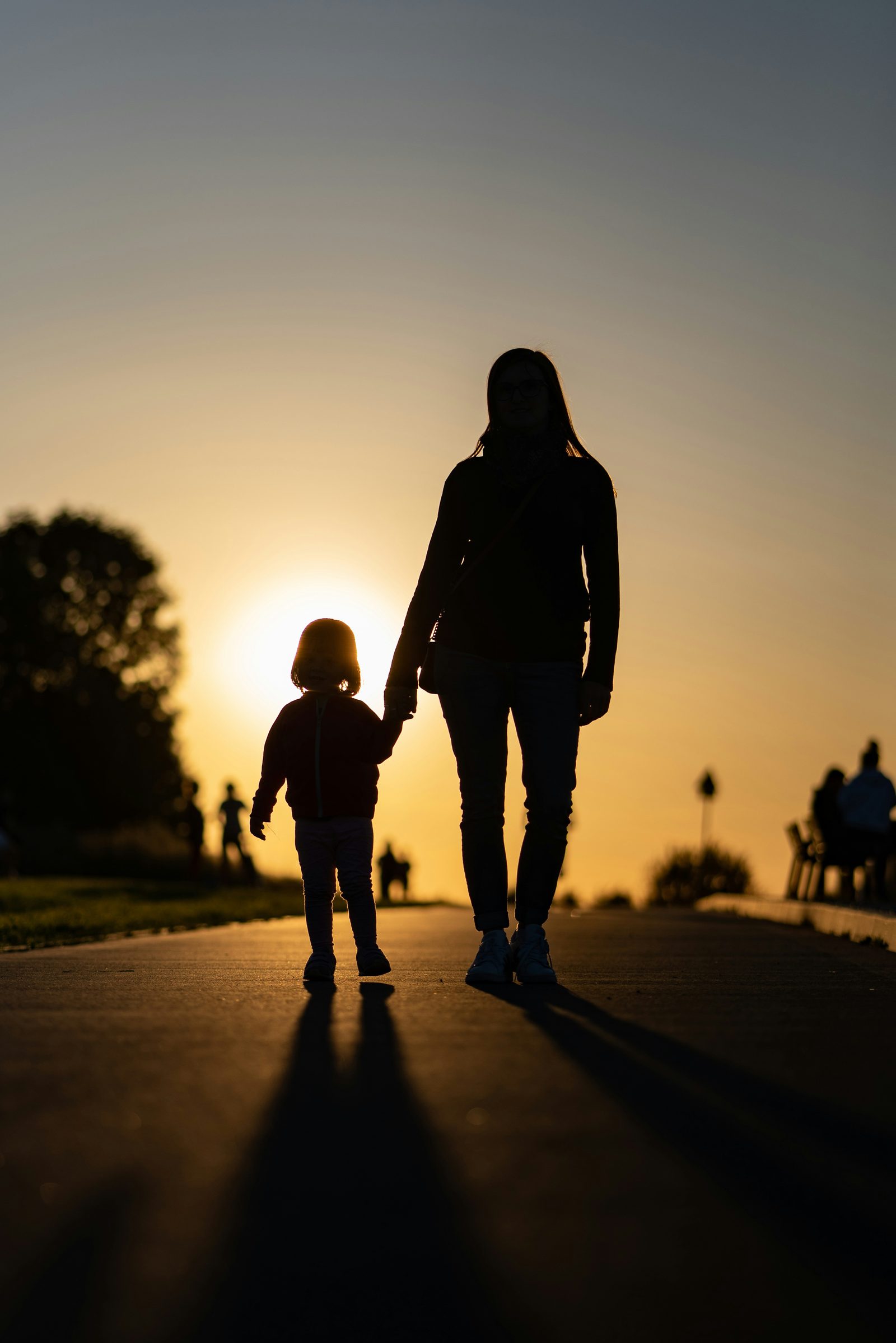 A parent carrying a baby, walking home
